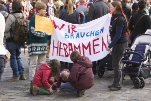 Zwei Frauen halten ein Transparent mit der Aufschrift "Wir brauchen Hebammen"